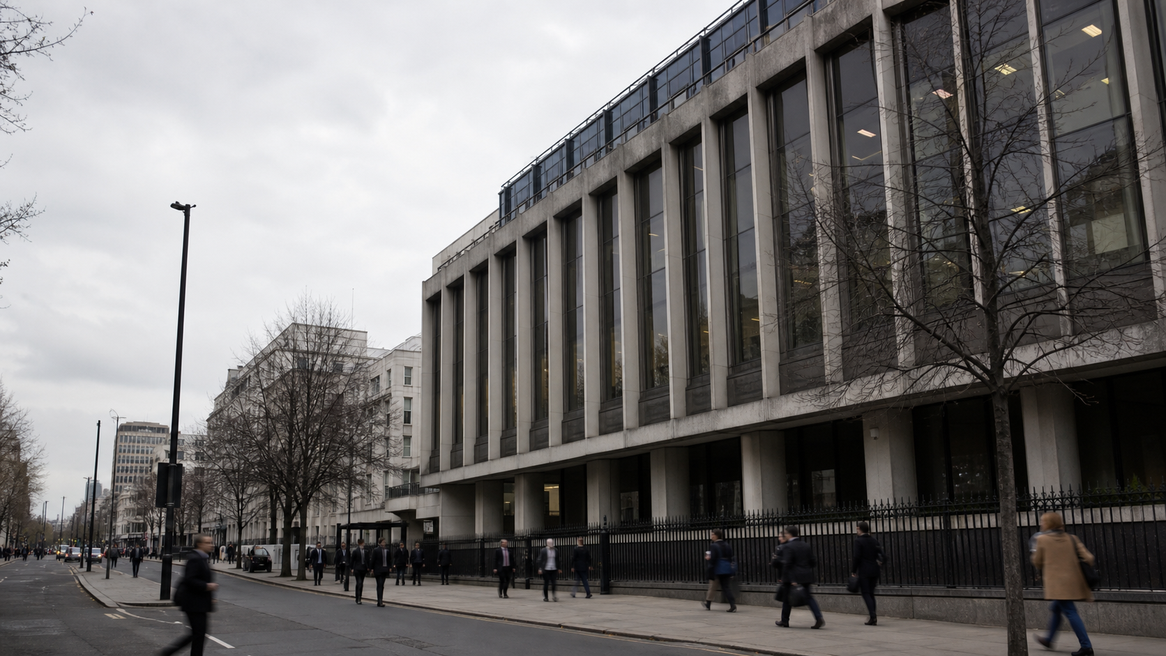 Exterior of the Premier League headquarters in London on an overcast afternoon, with pedestrians passing and room for headline text in the sky area; no visible logos or readable signs.