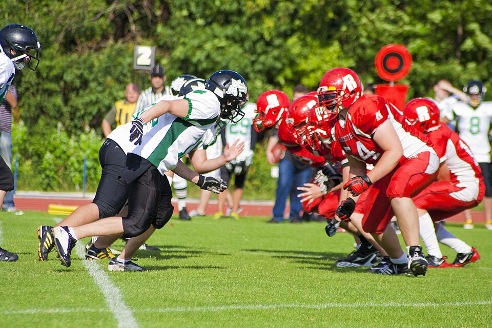American football teams line up at the line of scrimmage during an outdoor tournament.