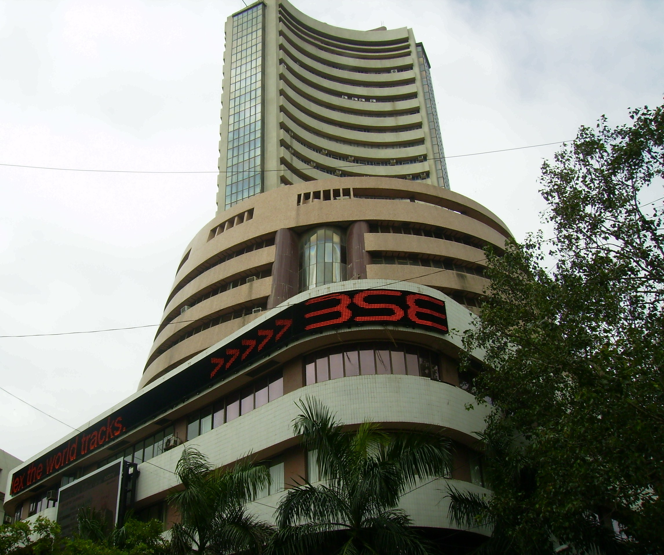 The Bombay Stock Exchange building and its red electronic ticker rise above trees in Mumbai.