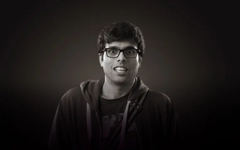 Genuine monochrome portrait of comedian and voice-over artist Aamer Peeran, wearing glasses and a hoodie.