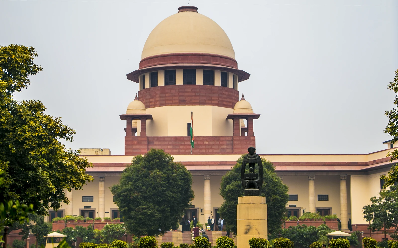 Central Wing of the Supreme Court of India in New Delhi under a bright sky.